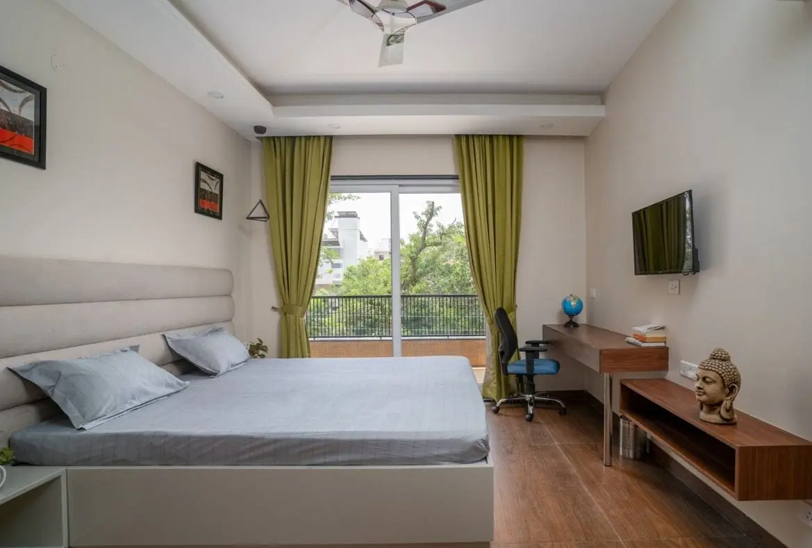A private room at Commune Anant with a queen bed, TV and garden view
