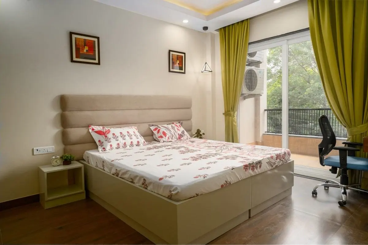 Queen bed and work desk in a Commune Anant room