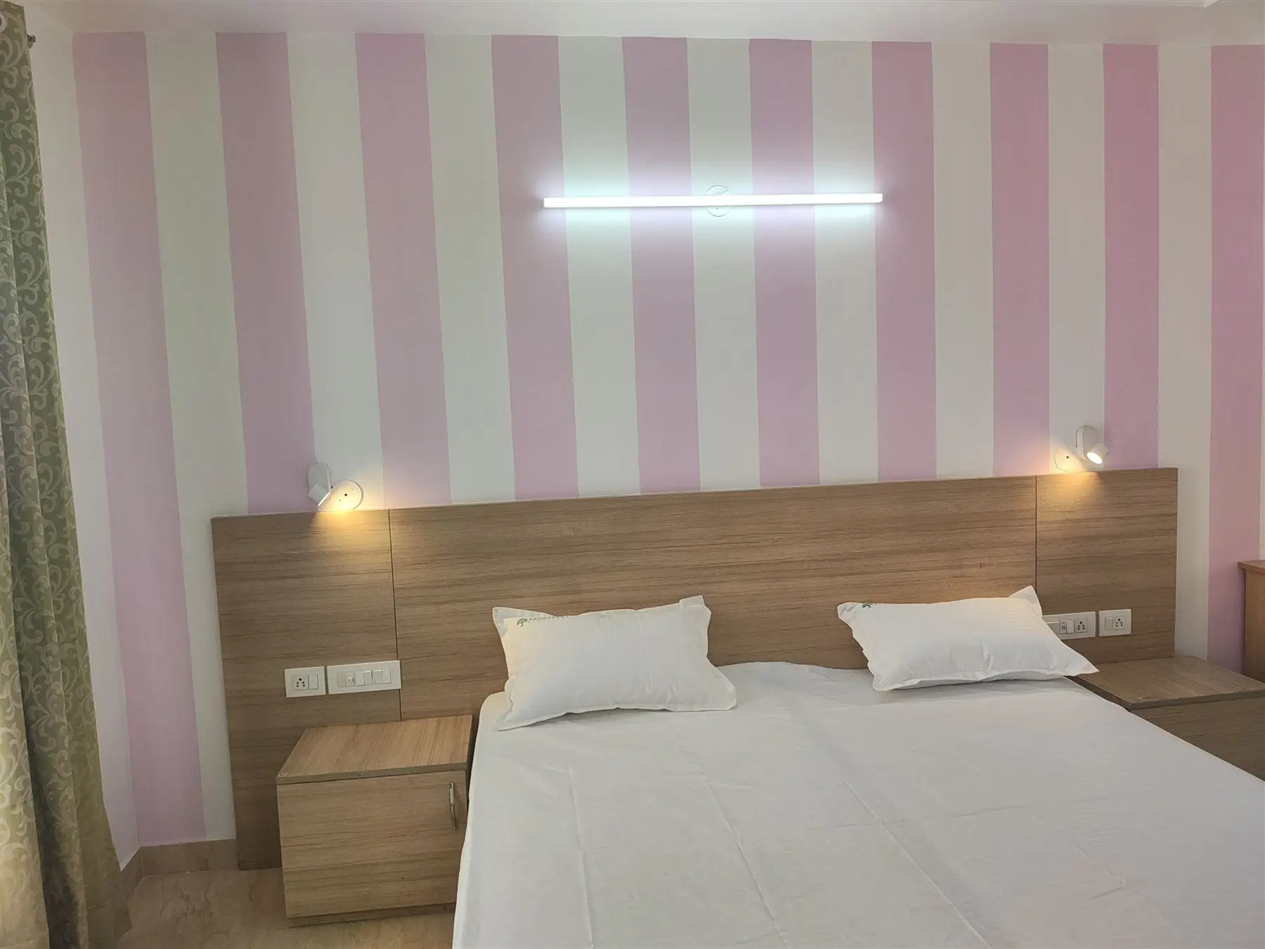 A bright sharing room at Commune Collective with twin beds and a striped feature wall