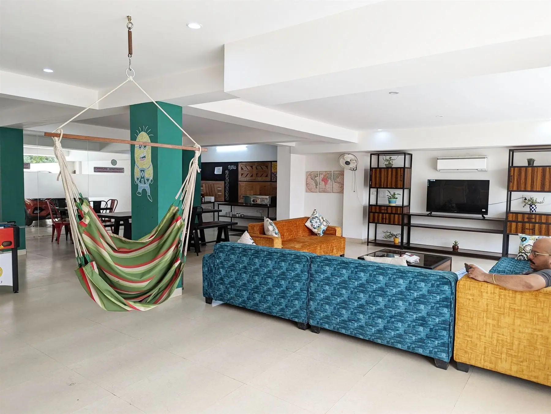 The lounge at Commune Florence with a hammock chair and teal pillar