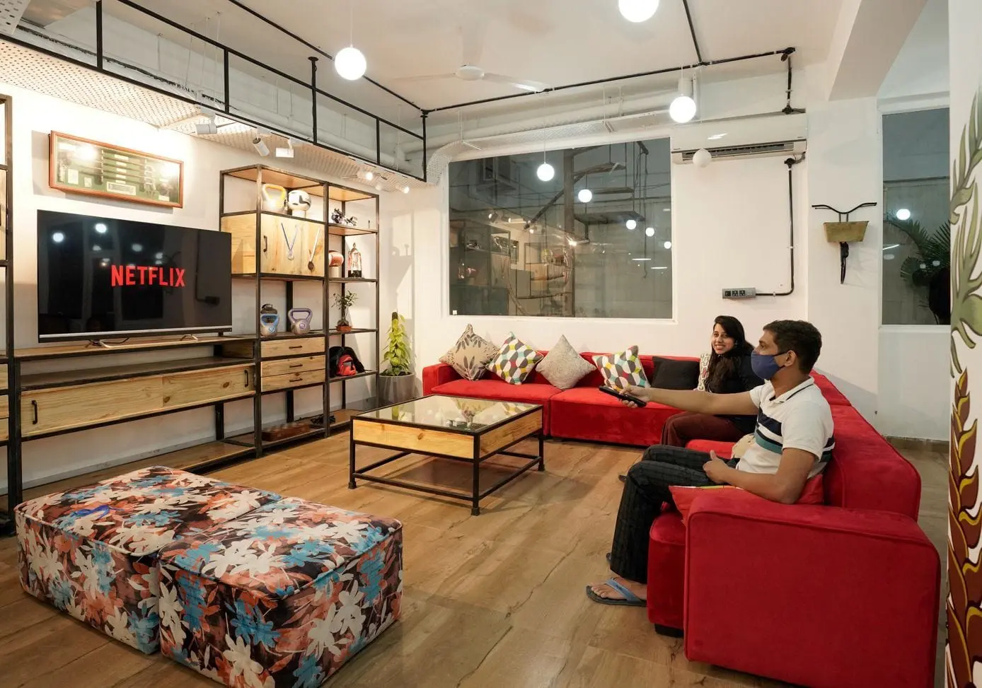 Communrs relaxing on the red sofas in the Commune Greenwood lounge