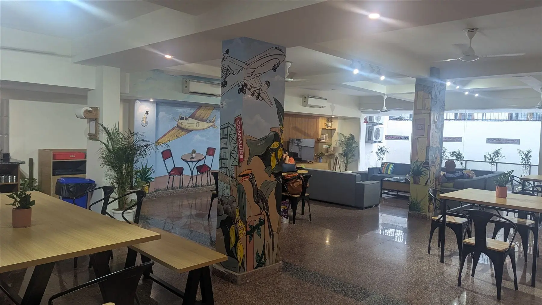 The lounge at Commune Nova with long tables and a mural wall