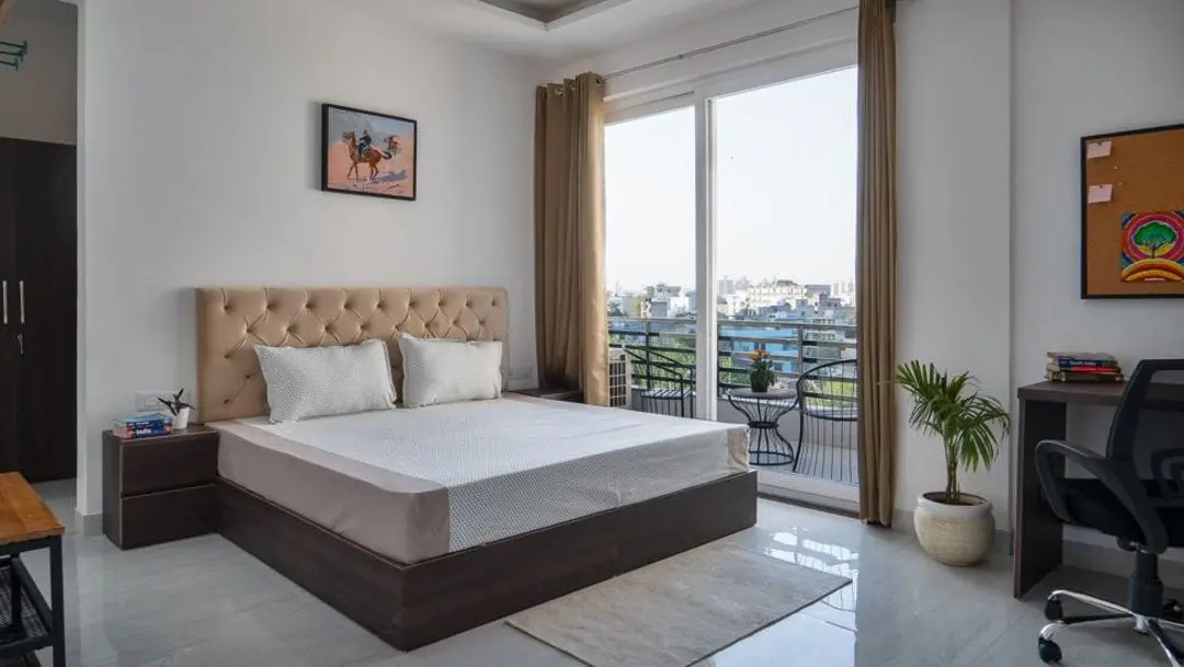 A private room at Commune Quartex with a queen bed and balcony doors