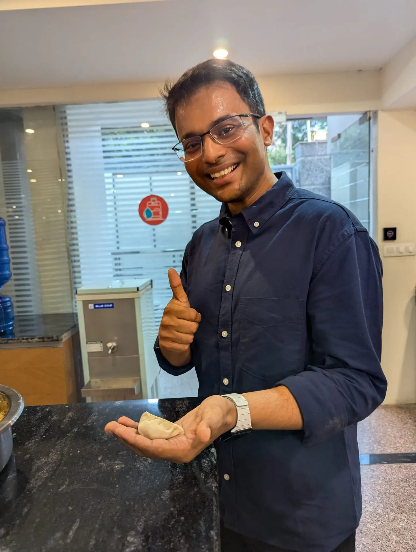 A Communr giving a thumbs up while holding a freshly folded momo