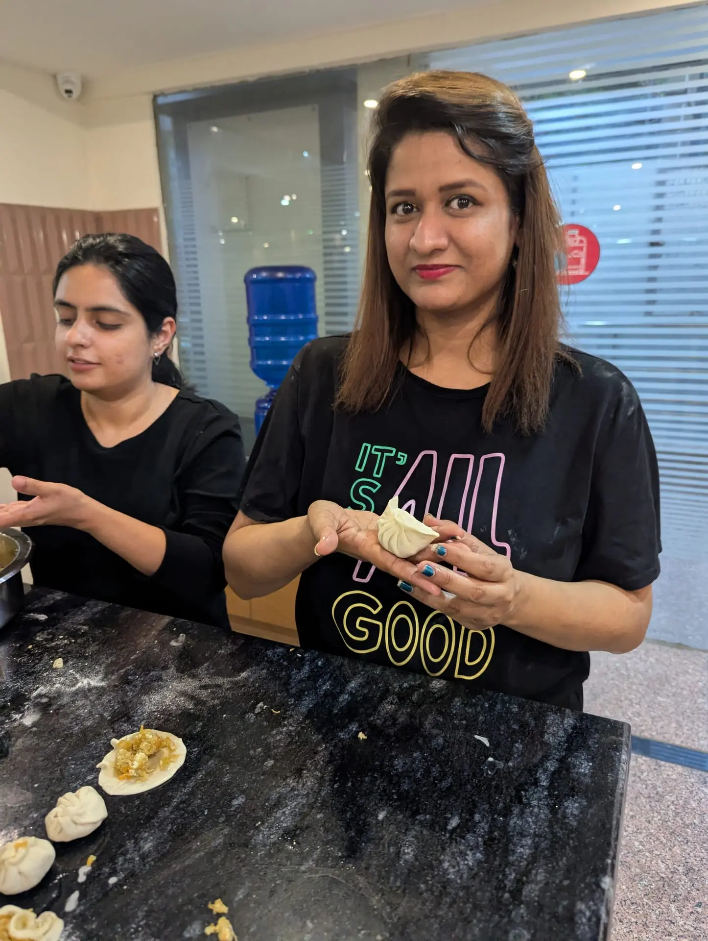 Two Communrs shaping momos in the community kitchen
