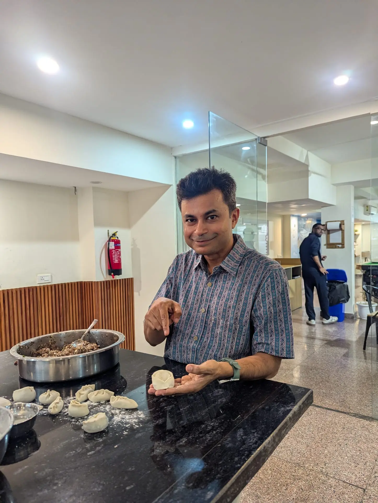 A Communr showing a momo in progress beside a big bowl of filling