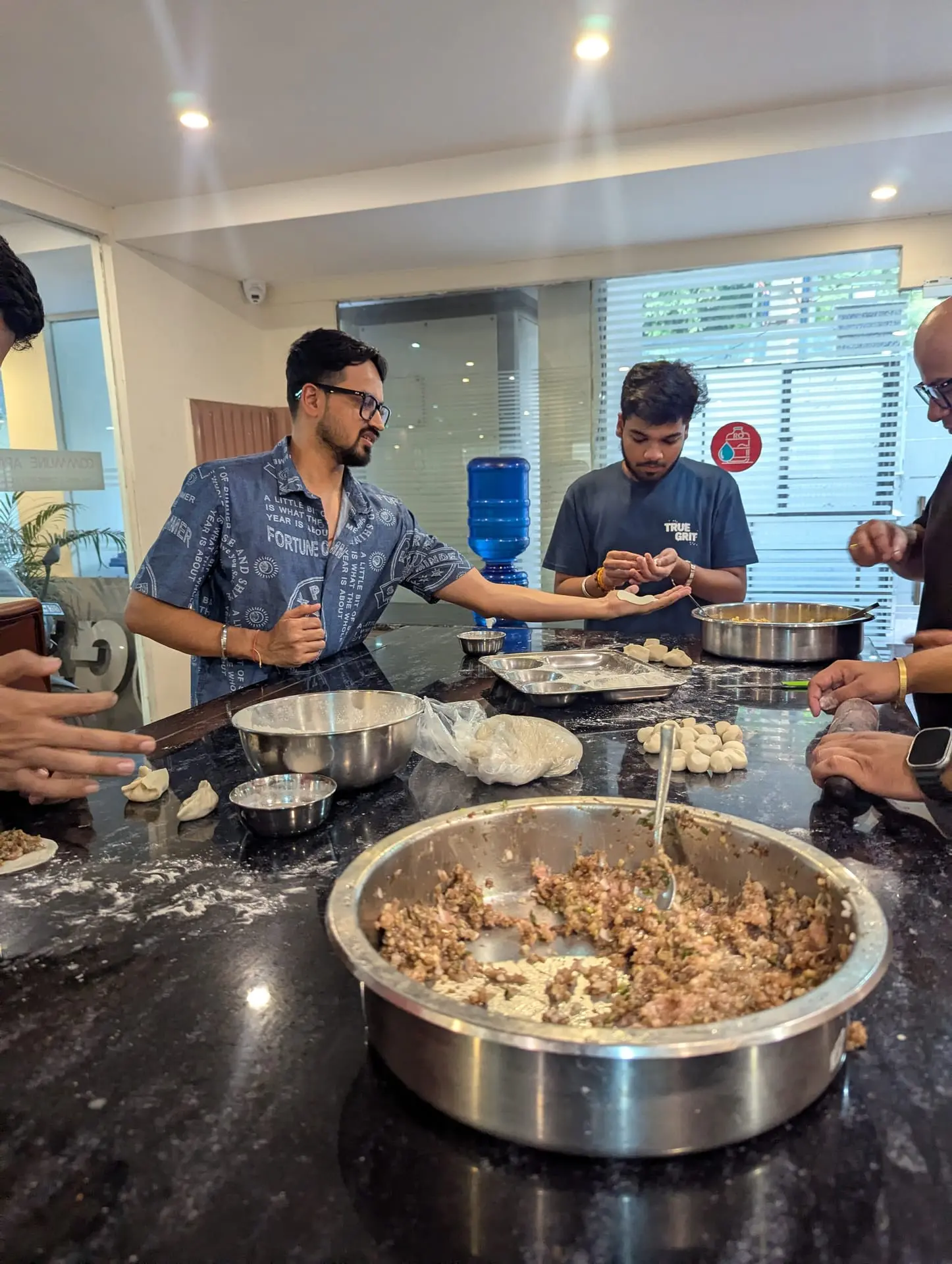 A Communr pleating a momo over a big bowl of filling