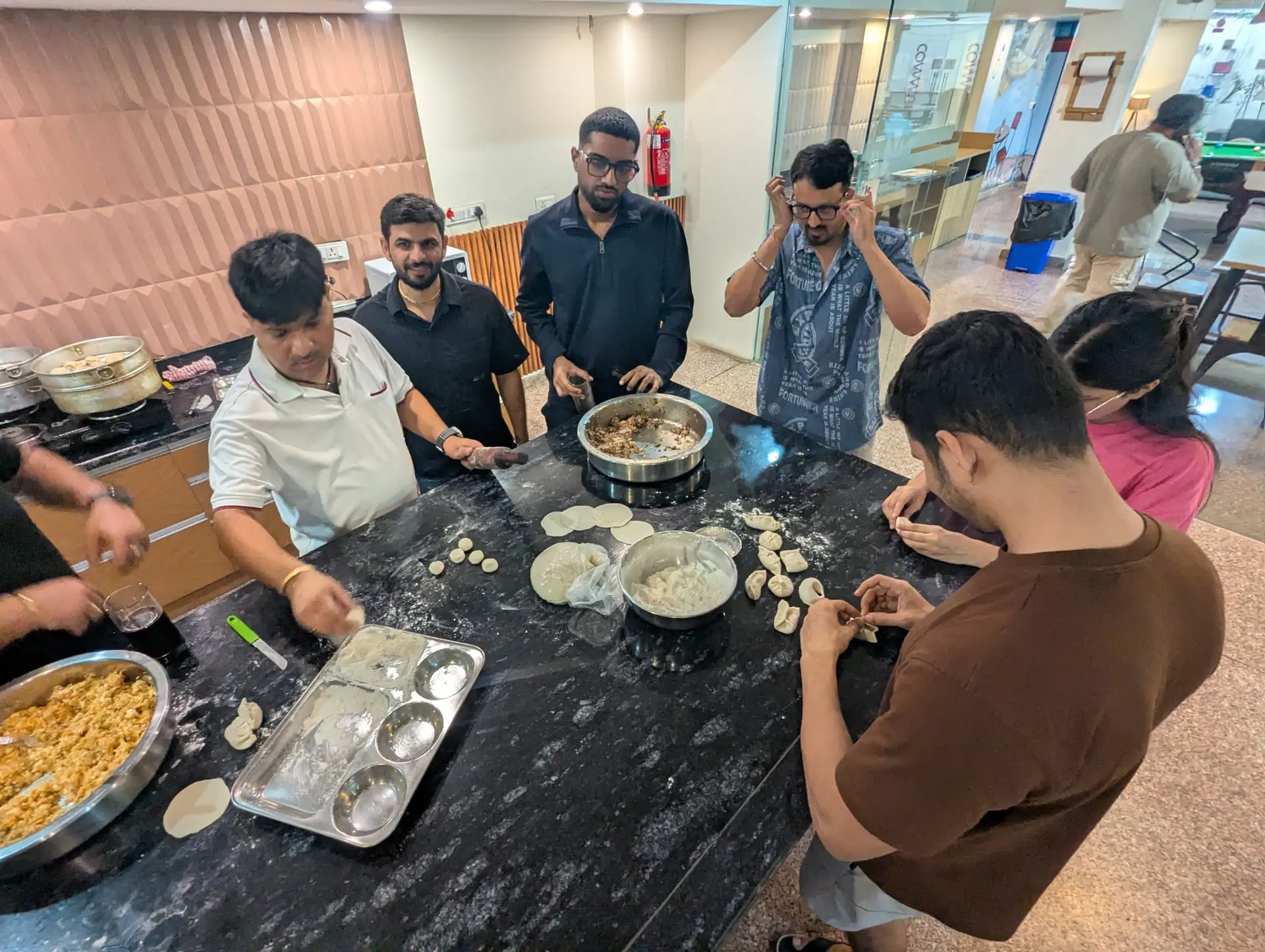 Communrs laughing as they fold momos in the community kitchen