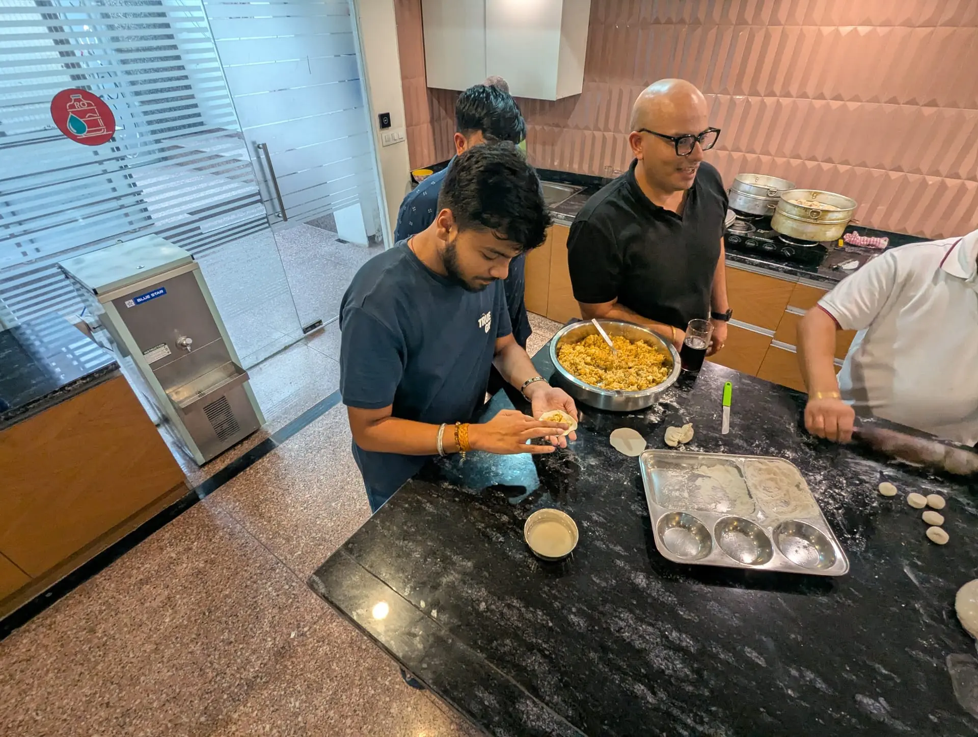 A Communr filling a momo while others work around the community kitchen