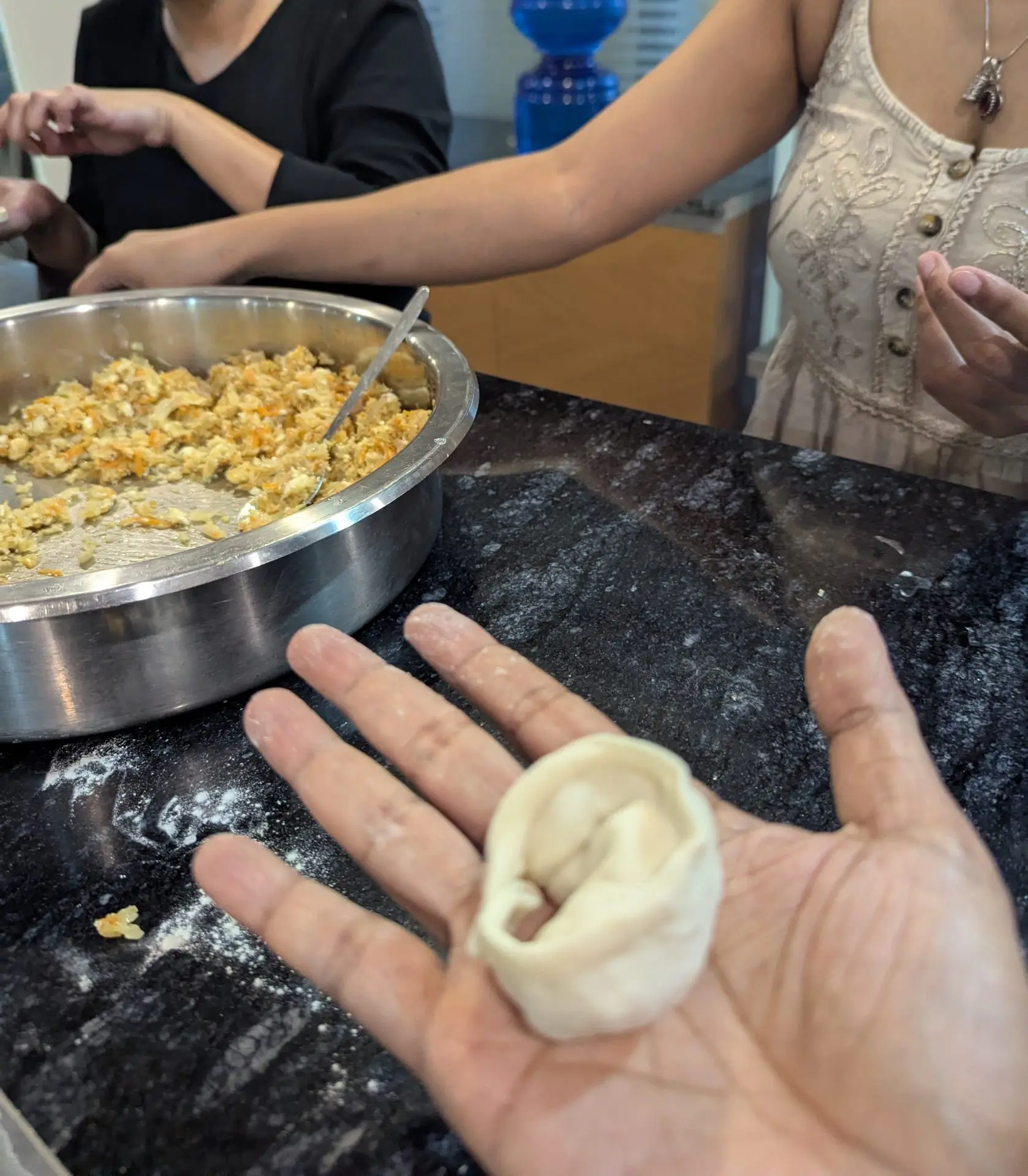Close-up of a hand holding a neatly pleated momo