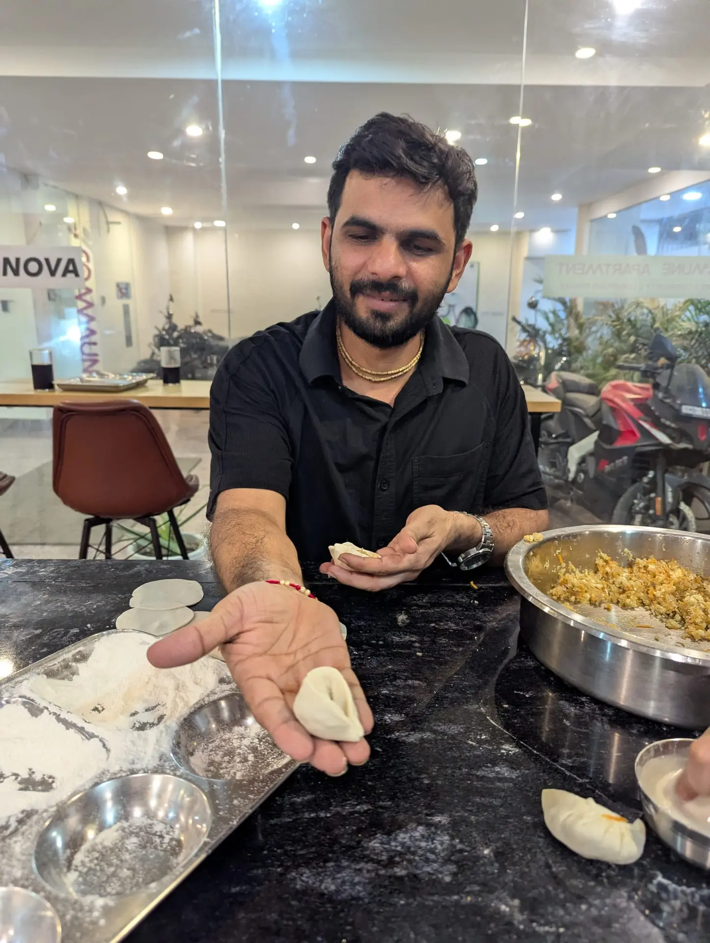 A Communr holding up a finished momo in the community kitchen
