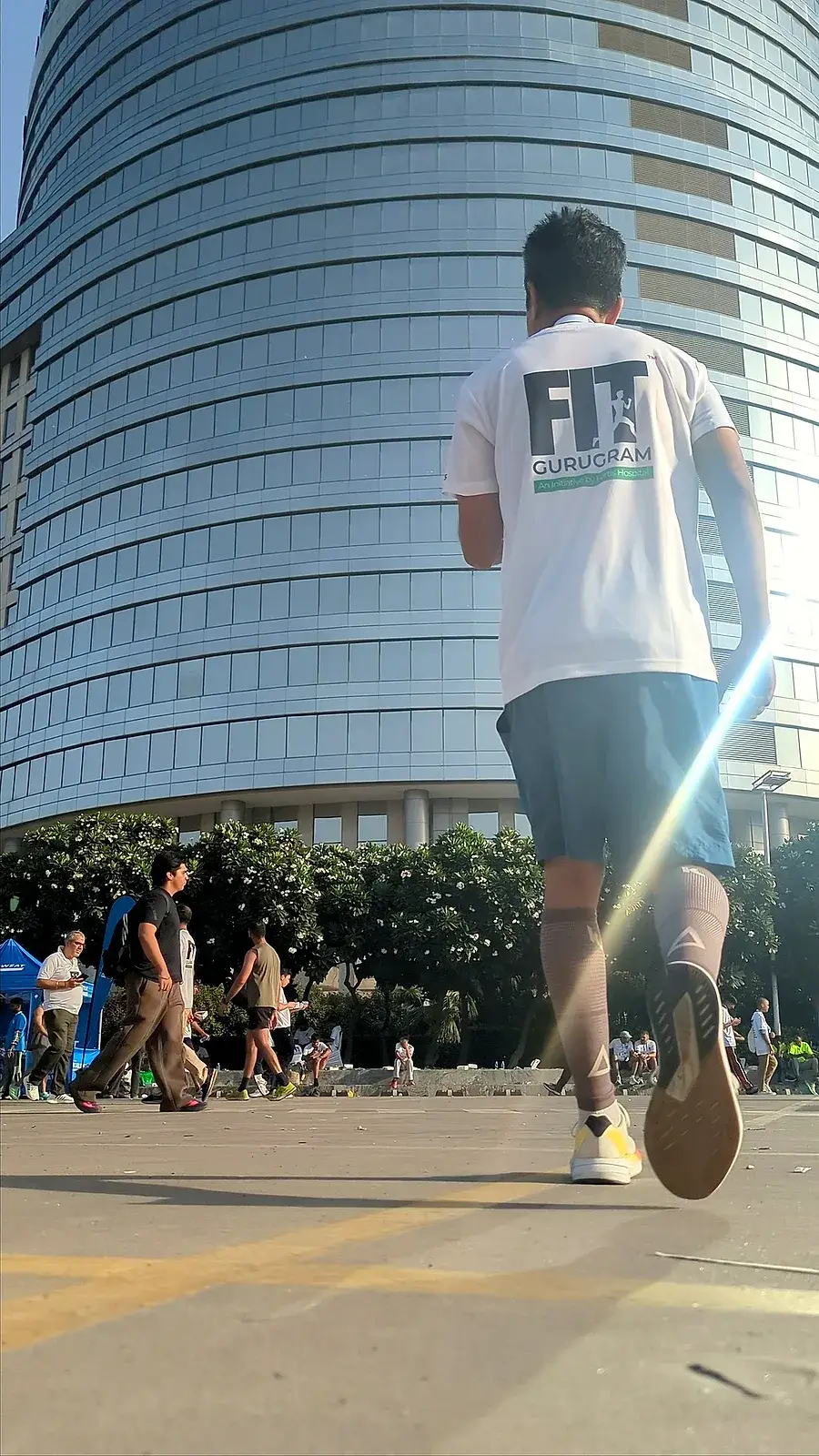 A Communr in a FIT Gurugram tee running past the glass tower on the marathon route