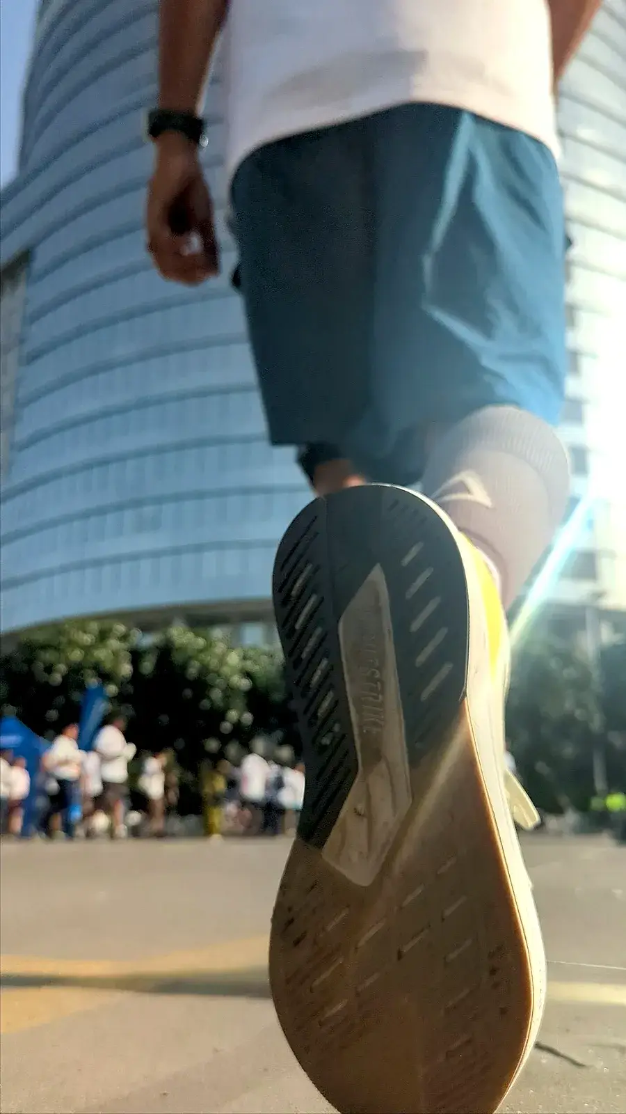 A low shot of a runner's shoe mid-stride, with the morning sun behind