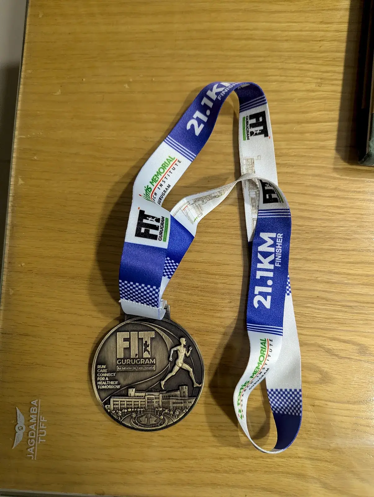 The FIT Gurugram 21.1 km finisher's medal on its blue and white lanyard