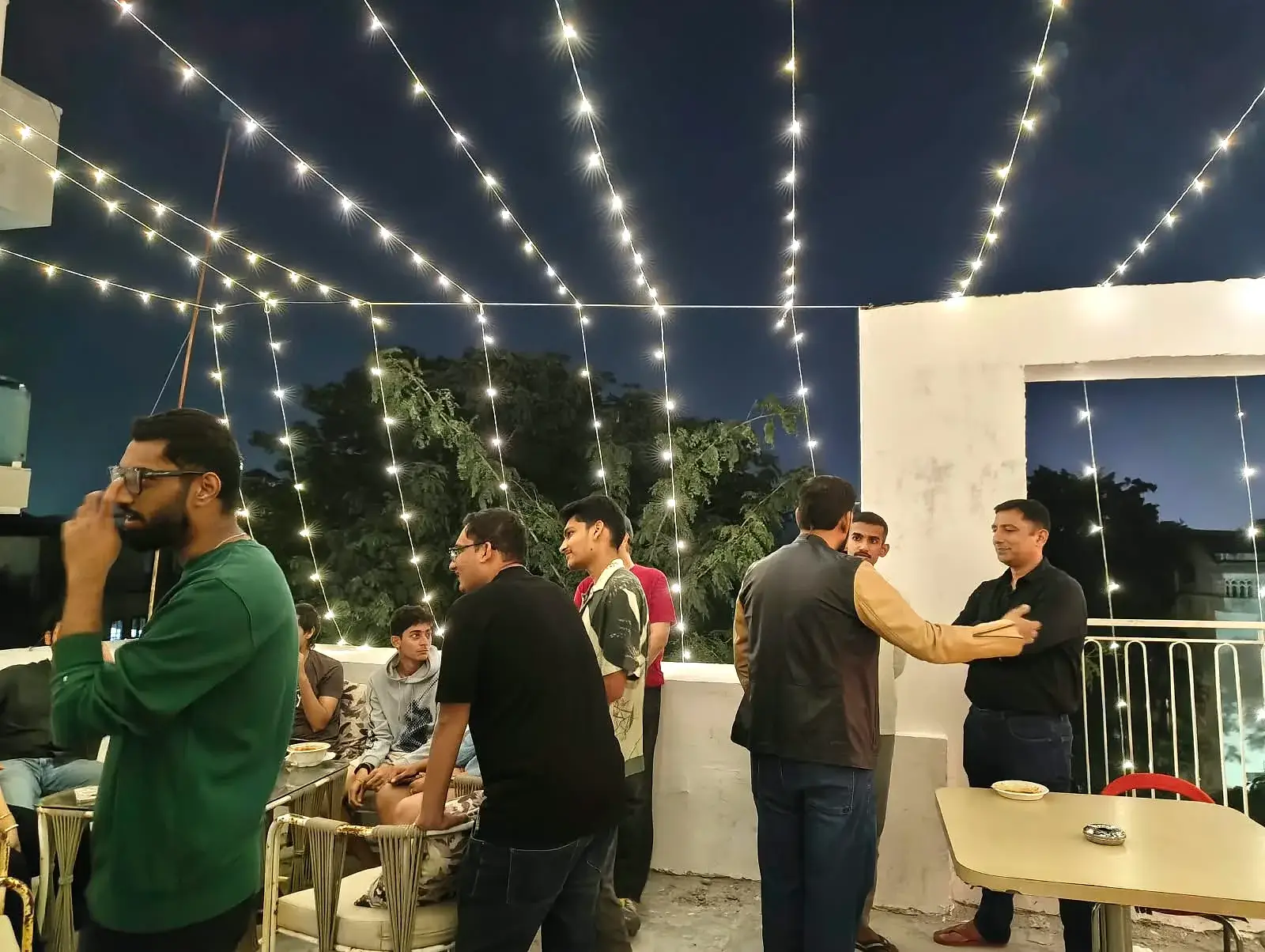 Communrs standing and chatting by the rooftop railing