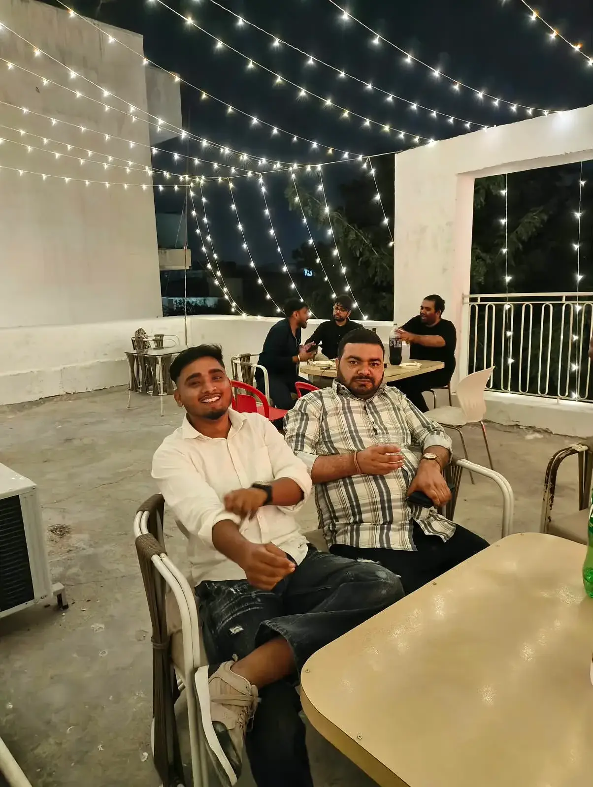 Two Communrs sitting back under the string lights