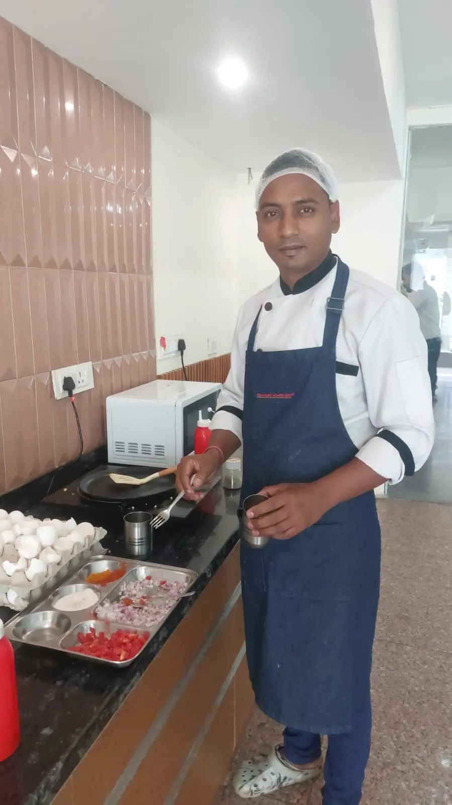 A chef at the live counter with a tray of eggs ready to cook