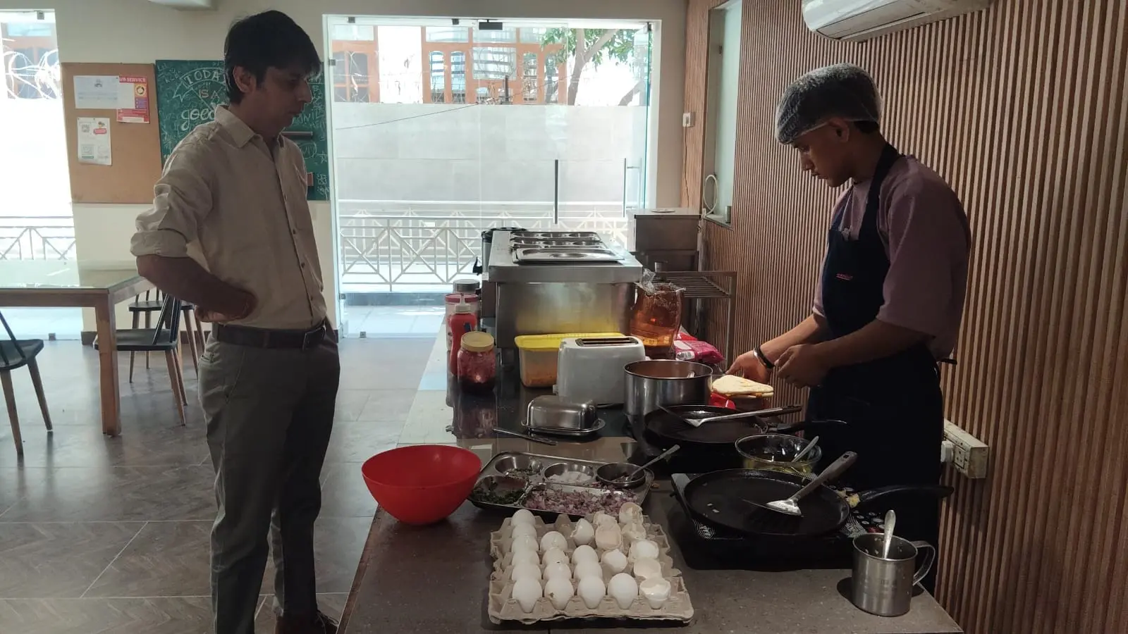 A chef cooking at the live breakfast counter while a resident waits