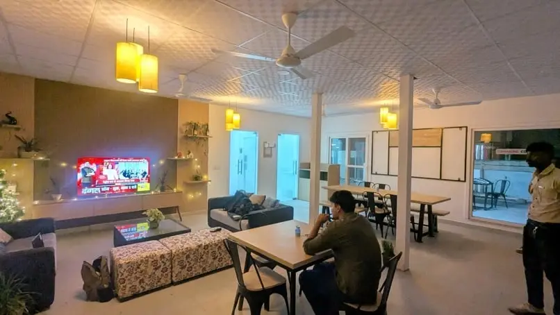 The lounge at Commune Collective, with sofas, a TV wall and dining tables